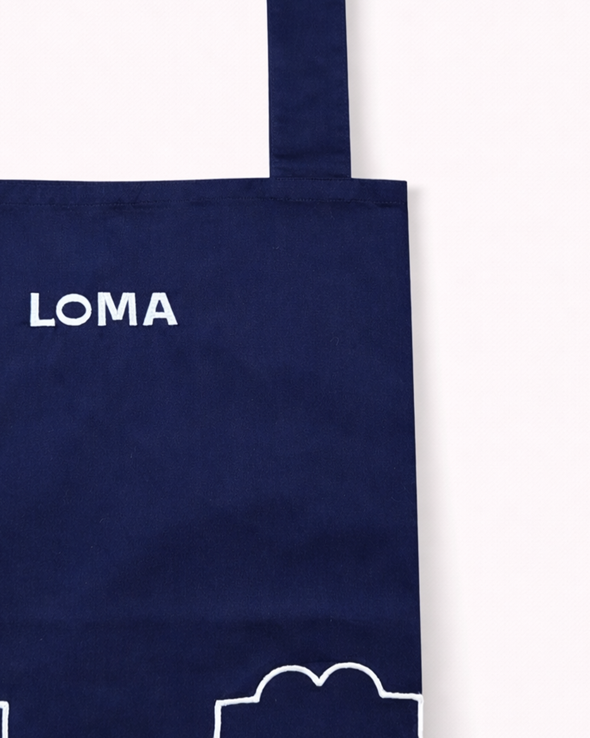 Close up of navy blue cotton apron embroidered with LOMA's logo in white front view