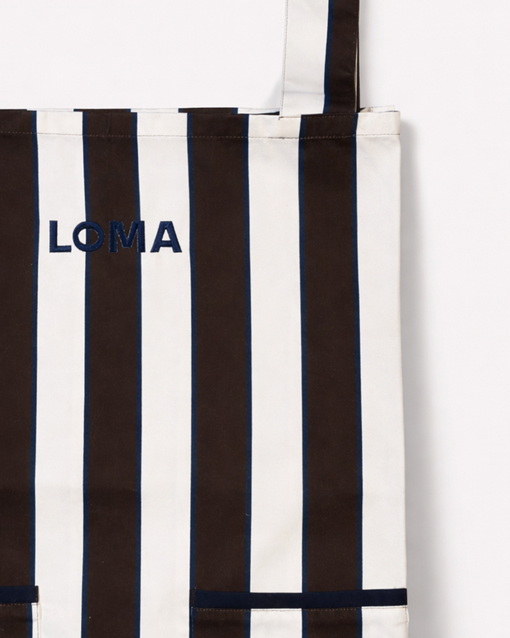 Close up of striped cotton apron in chocolate brown and white embroidered with LOMA's logo in navy blue front view