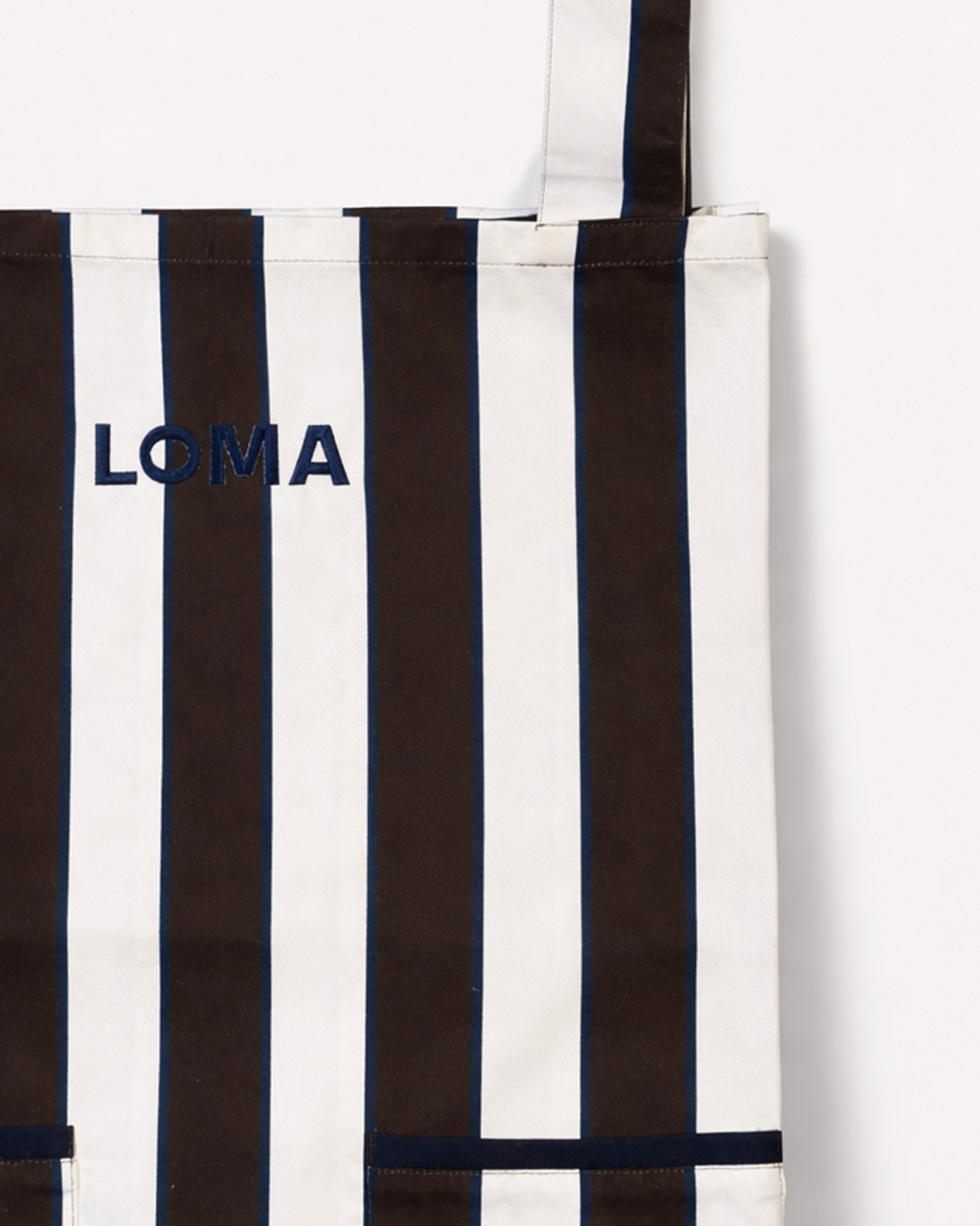 Close up of striped cotton apron in chocolate brown and white embroidered with LOMA's logo in navy blue front view